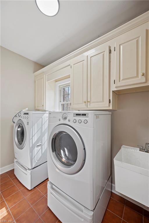 clothes washing area with a sink, baseboards, washer and dryer, cabinet space, and tile patterned floors