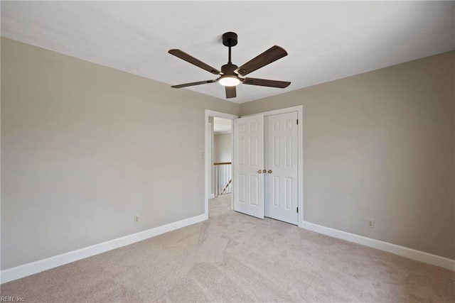 unfurnished bedroom featuring ceiling fan, baseboards, a closet, and light colored carpet