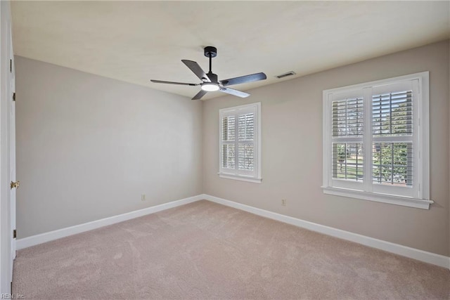 spare room with light carpet, baseboards, visible vents, and ceiling fan