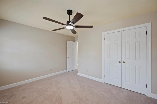 unfurnished bedroom featuring carpet floors, a closet, baseboards, and a ceiling fan