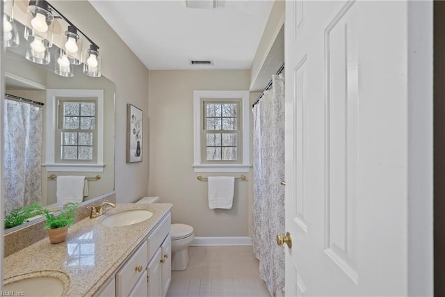 full bathroom with baseboards, a sink, toilet, and double vanity