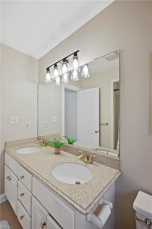 bathroom with double vanity, a sink, and toilet