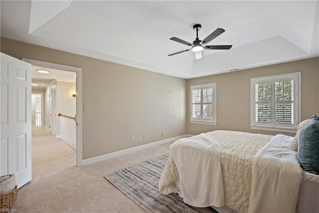 bedroom featuring ceiling fan, baseboards, a raised ceiling, and light colored carpet