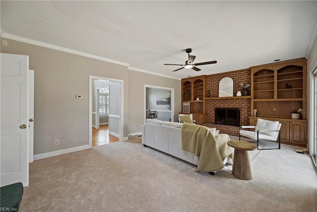 living area with built in shelves, light colored carpet, a fireplace, baseboards, and crown molding