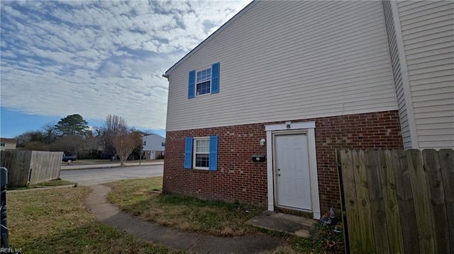 exterior space featuring fence and brick siding