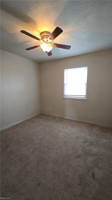 empty room with a textured ceiling, carpet, visible vents, and baseboards