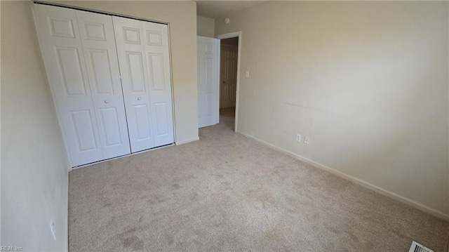 unfurnished bedroom with carpet, visible vents, baseboards, and a closet