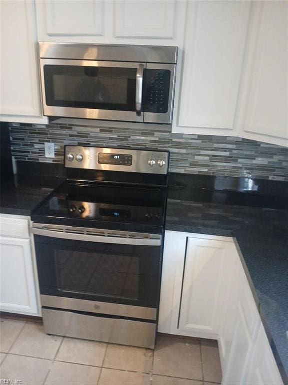 kitchen featuring appliances with stainless steel finishes, white cabinets, backsplash, and light tile patterned flooring