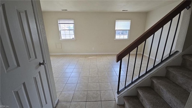 entrance foyer featuring light tile patterned floors, plenty of natural light, stairway, and baseboards