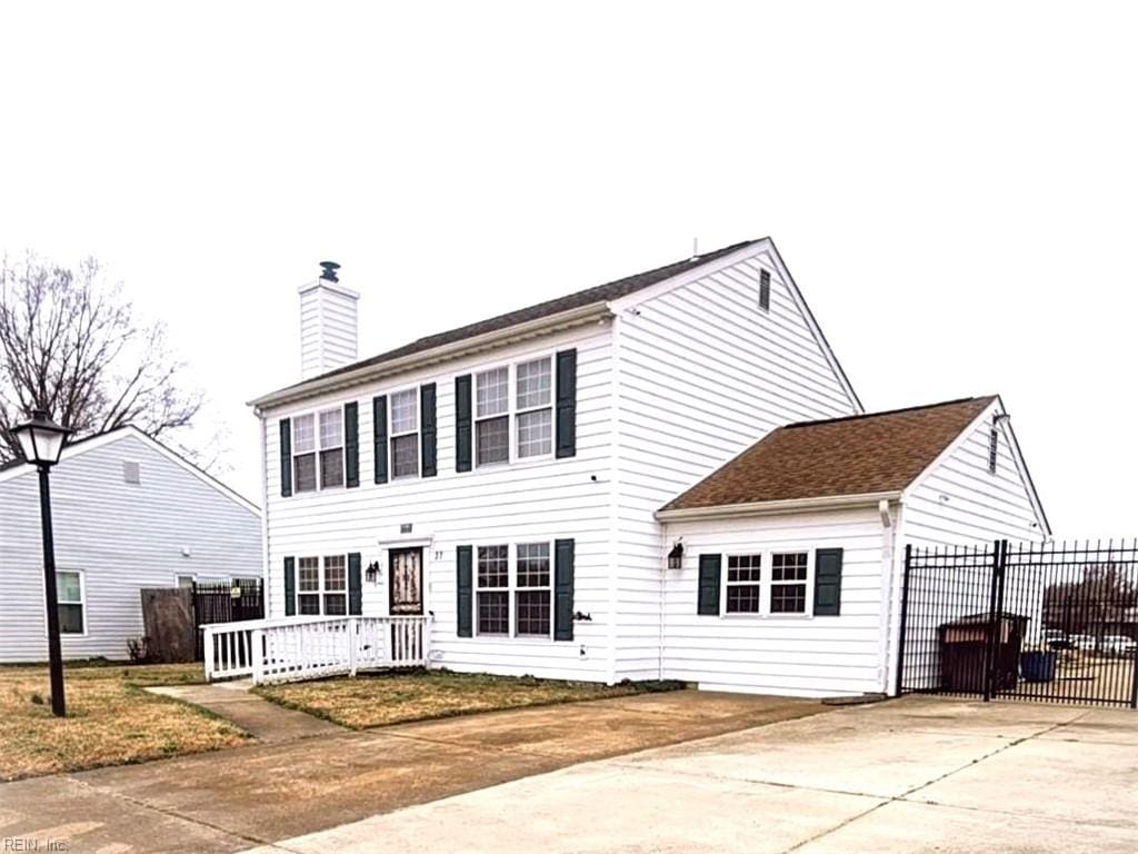 colonial inspired home featuring a chimney and fence