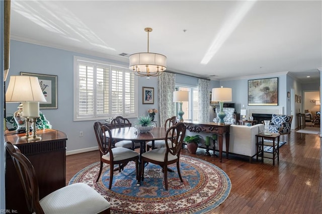 dining area featuring ornamental molding, dark wood-type flooring, a fireplace, and visible vents