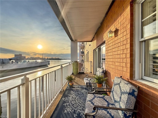 balcony at dusk featuring a water view