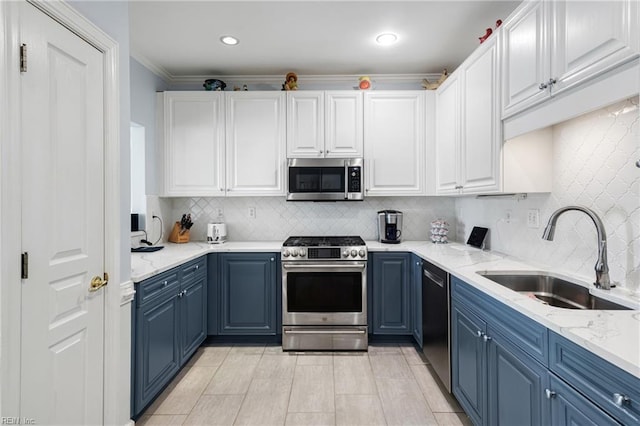 kitchen with appliances with stainless steel finishes, blue cabinets, a sink, and white cabinetry