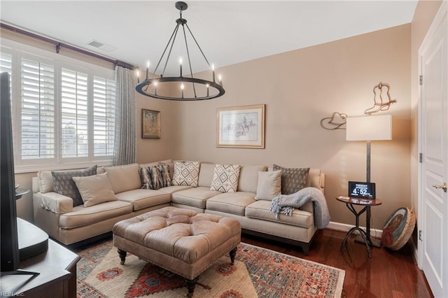 living room featuring a chandelier, wood finished floors, visible vents, and baseboards