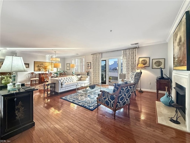 living room with wood-type flooring, a fireplace, crown molding, and visible vents