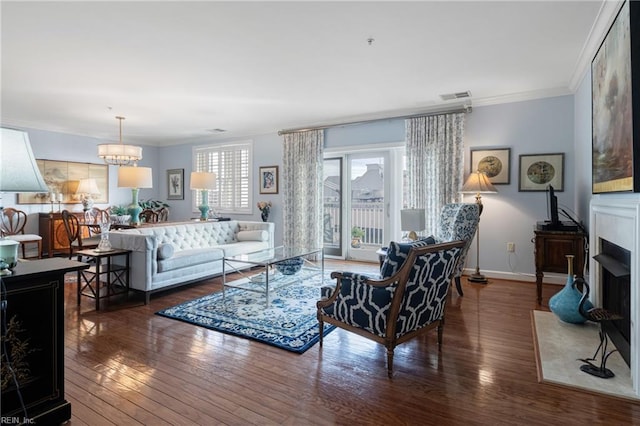 living area with ornamental molding, a fireplace with flush hearth, a chandelier, baseboards, and hardwood / wood-style flooring