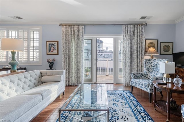 living area featuring visible vents, crown molding, and wood finished floors