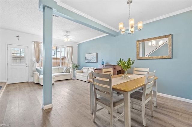 dining space with baseboards, ornamental molding, wood finished floors, a textured ceiling, and ceiling fan with notable chandelier