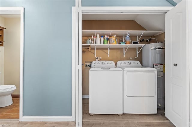 laundry area with electric water heater, laundry area, wood finished floors, baseboards, and washer and clothes dryer