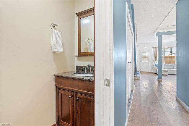 bathroom with decorative columns, baseboards, wood finished floors, and vanity