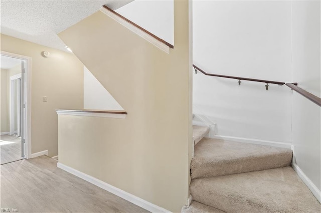 stairway with a textured ceiling and baseboards