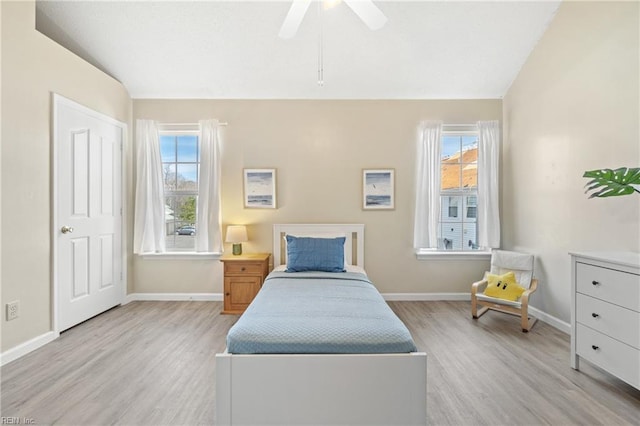 bedroom with light wood-style floors, lofted ceiling, baseboards, and a ceiling fan