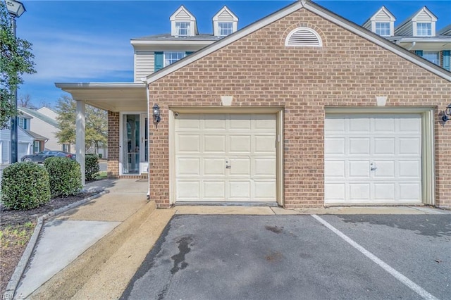 view of front of home with an attached garage, aphalt driveway, and brick siding