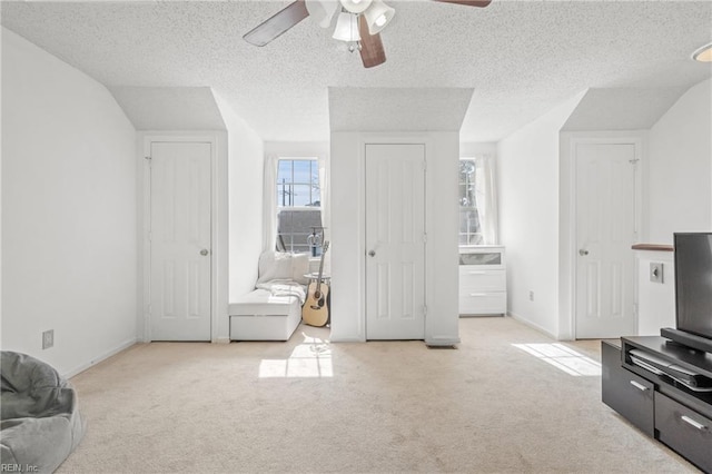 interior space featuring a ceiling fan, carpet flooring, a textured ceiling, and baseboards