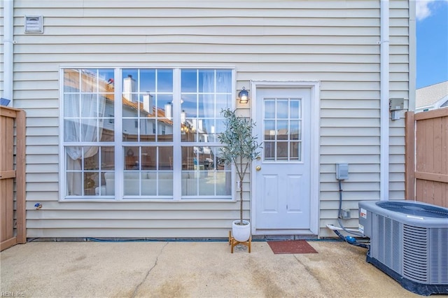 entrance to property with central AC unit, a patio area, and fence