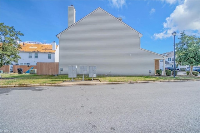 view of property exterior with a chimney and fence