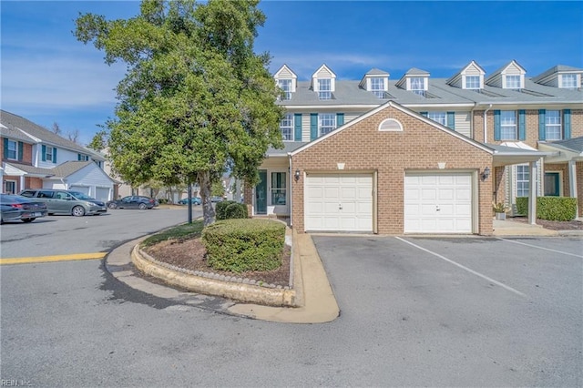 townhome / multi-family property with a garage, a residential view, and brick siding