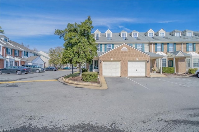 view of property featuring an attached garage, a residential view, and brick siding