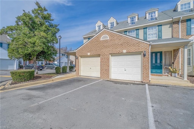 townhome / multi-family property featuring an attached garage, driveway, and brick siding