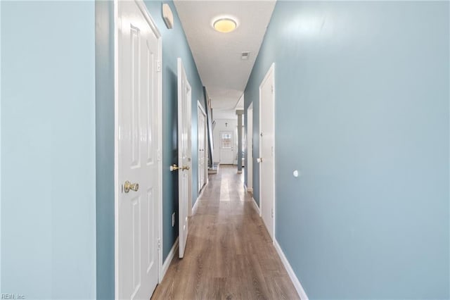 corridor featuring light wood-style floors and baseboards