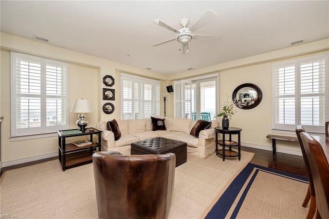 living room with a ceiling fan, visible vents, and baseboards