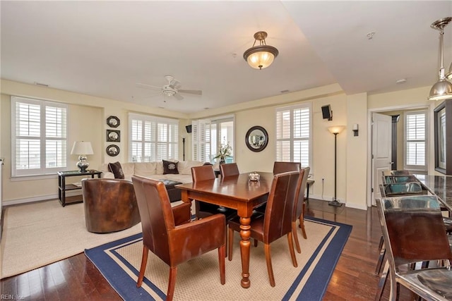 dining space with ceiling fan, baseboards, and dark wood finished floors