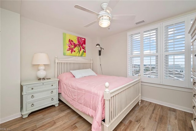 bedroom featuring light wood-style floors, baseboards, visible vents, and a ceiling fan