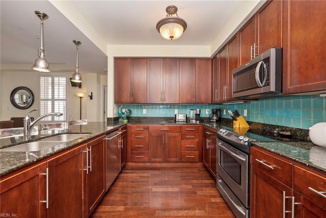 kitchen featuring appliances with stainless steel finishes, dark stone counters, a sink, and decorative backsplash