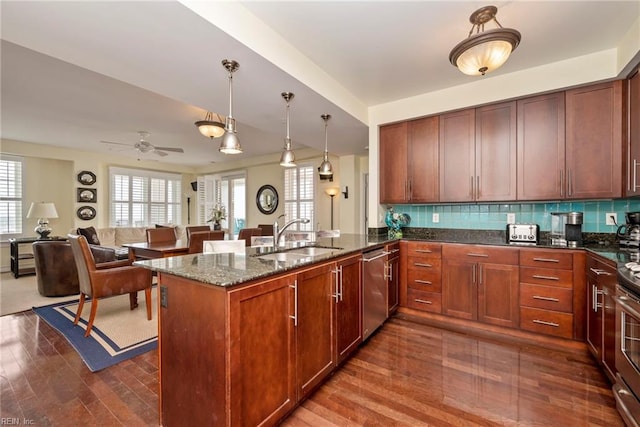 kitchen with dark stone counters, stainless steel appliances, backsplash, and a sink