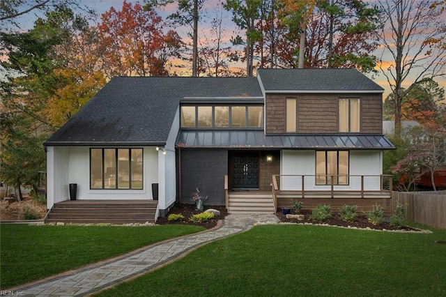 view of front of house with a porch, a standing seam roof, and a front yard