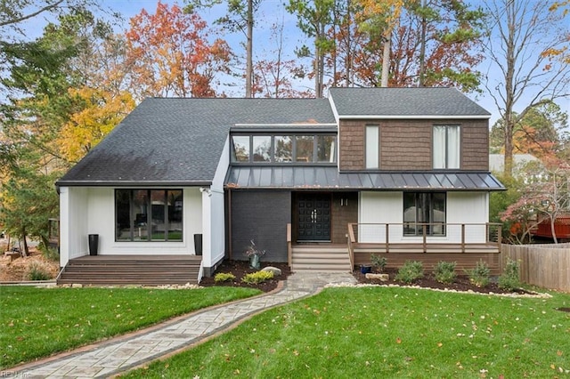 view of front of home featuring covered porch, metal roof, a front lawn, and a standing seam roof