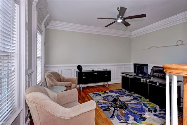 home office featuring a wainscoted wall, a ceiling fan, ornamental molding, and wood finished floors