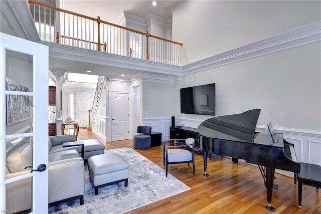 living room featuring light wood finished floors, ornamental molding, a decorative wall, and a wainscoted wall