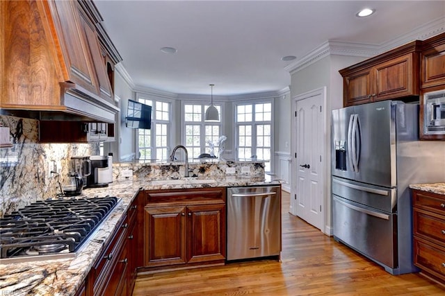 kitchen with a peninsula, plenty of natural light, stainless steel appliances, and a sink