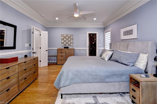 bedroom featuring light wood-style floors, crown molding, a spacious closet, and a ceiling fan