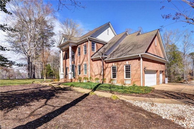 view of property exterior with an attached garage, driveway, and brick siding