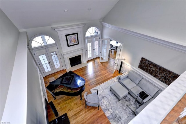 living room with lofted ceiling, a large fireplace, french doors, and wood finished floors