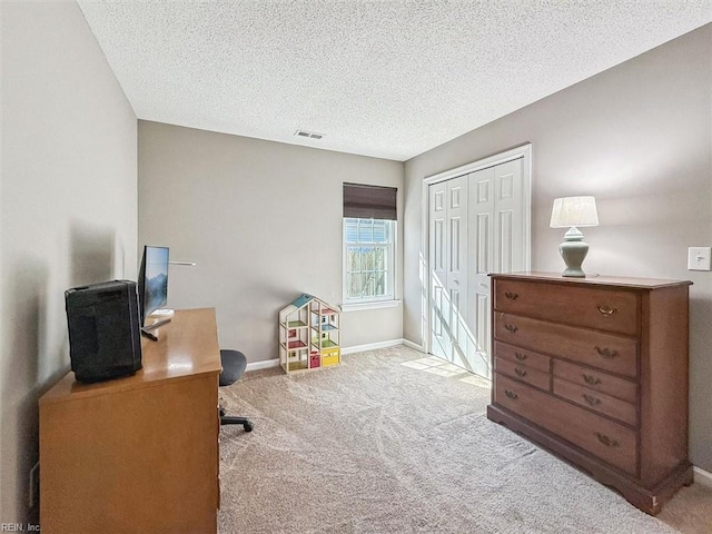 carpeted office space with a textured ceiling, visible vents, and baseboards