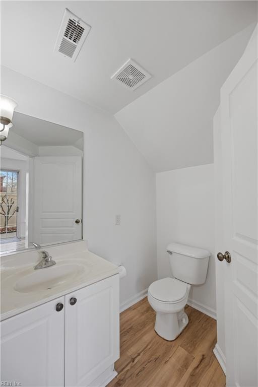 bathroom with toilet, visible vents, vaulted ceiling, and wood finished floors