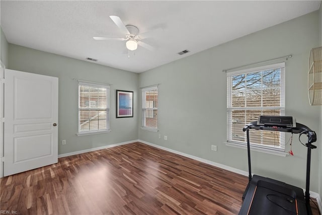 exercise room featuring visible vents, ceiling fan, baseboards, and wood finished floors